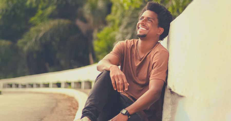 A man happily smiling while glancing at the sky above.