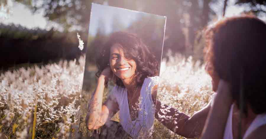 A photo of a happy woman staring at the mirror.