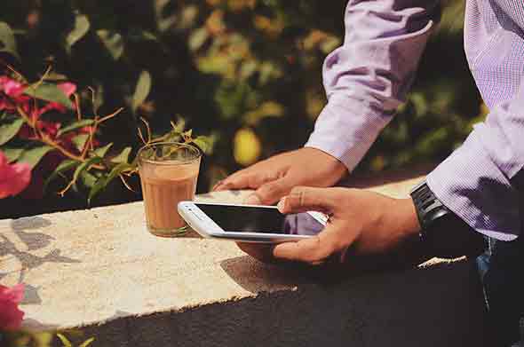  A photo of a man on his phone with a glass of drink on the side