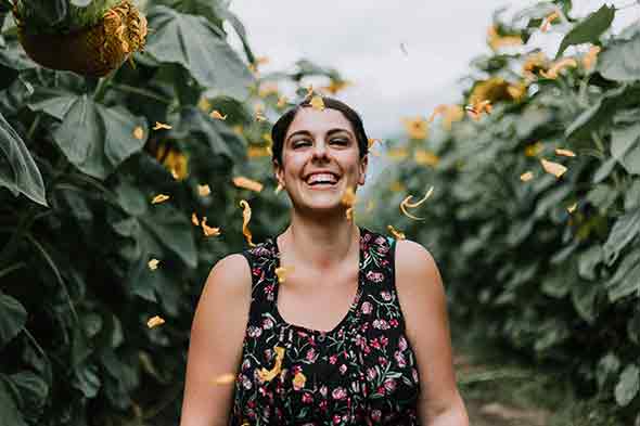 A photo of a woman laughing with flower petals falling down in the background