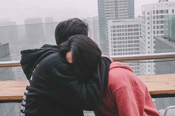 man in black hugging woman in red while sitting