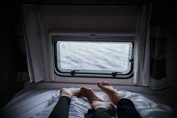  A photo showing a couple lying down in bed, facing a window 