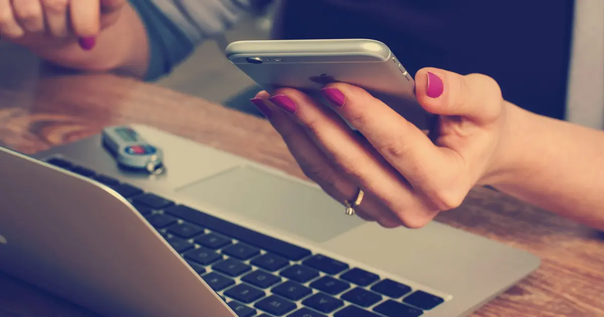 A person working on her laptop and phone.