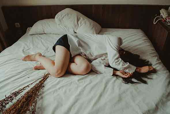 A woman in white long sleeves lying in the bed.