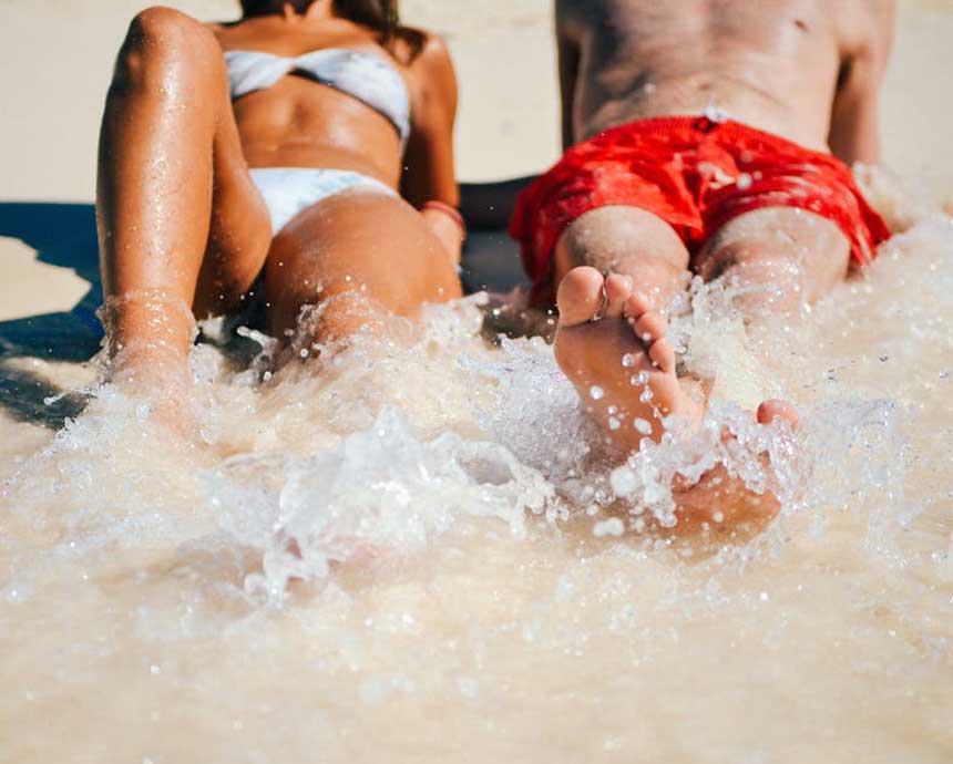 A couple sitting on the shore of the beach.